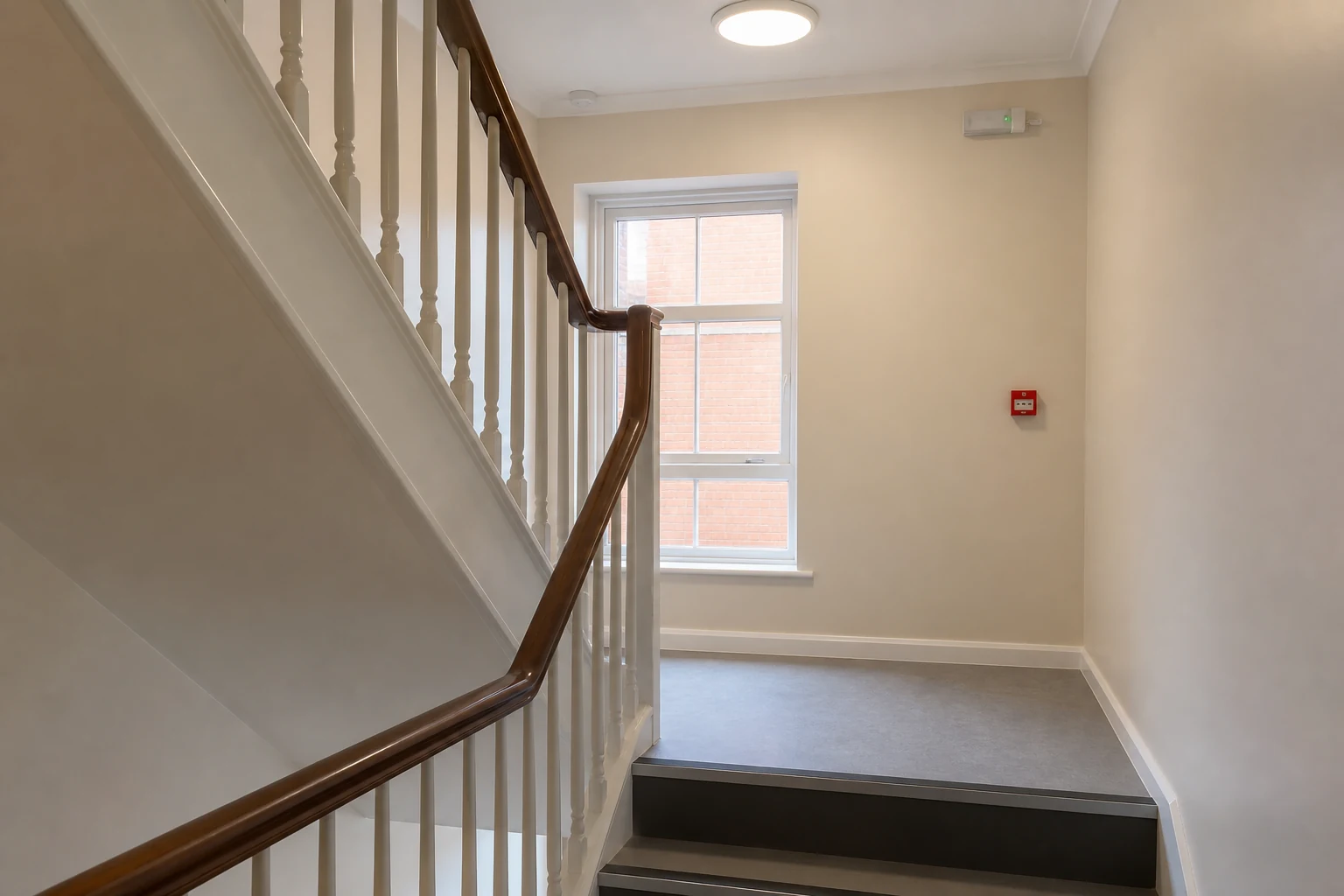 Empty building stairwell landing with lighting and fire safety fixtures.
